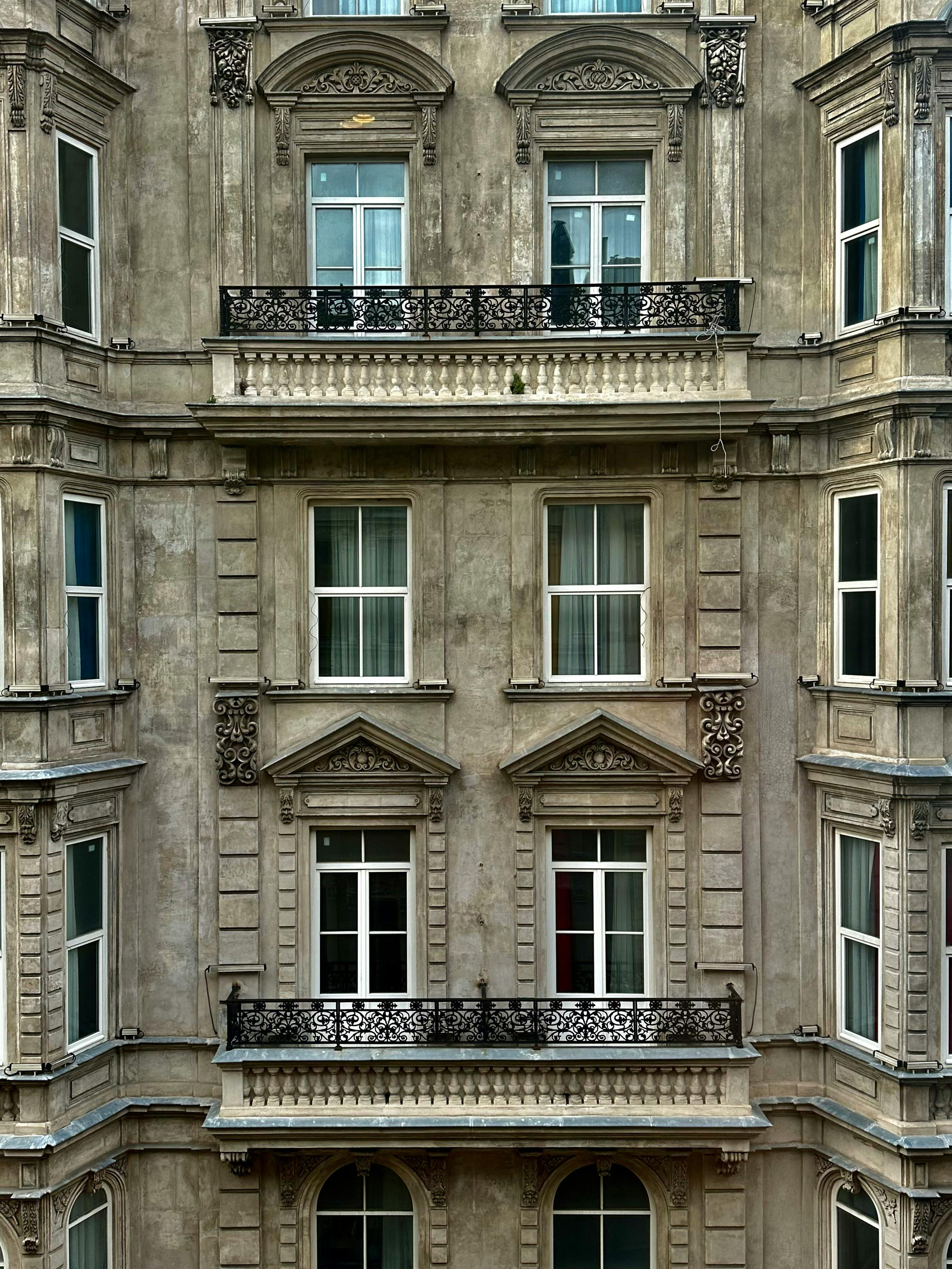 Stone heritage façade with classical ornament and tall wooden windows