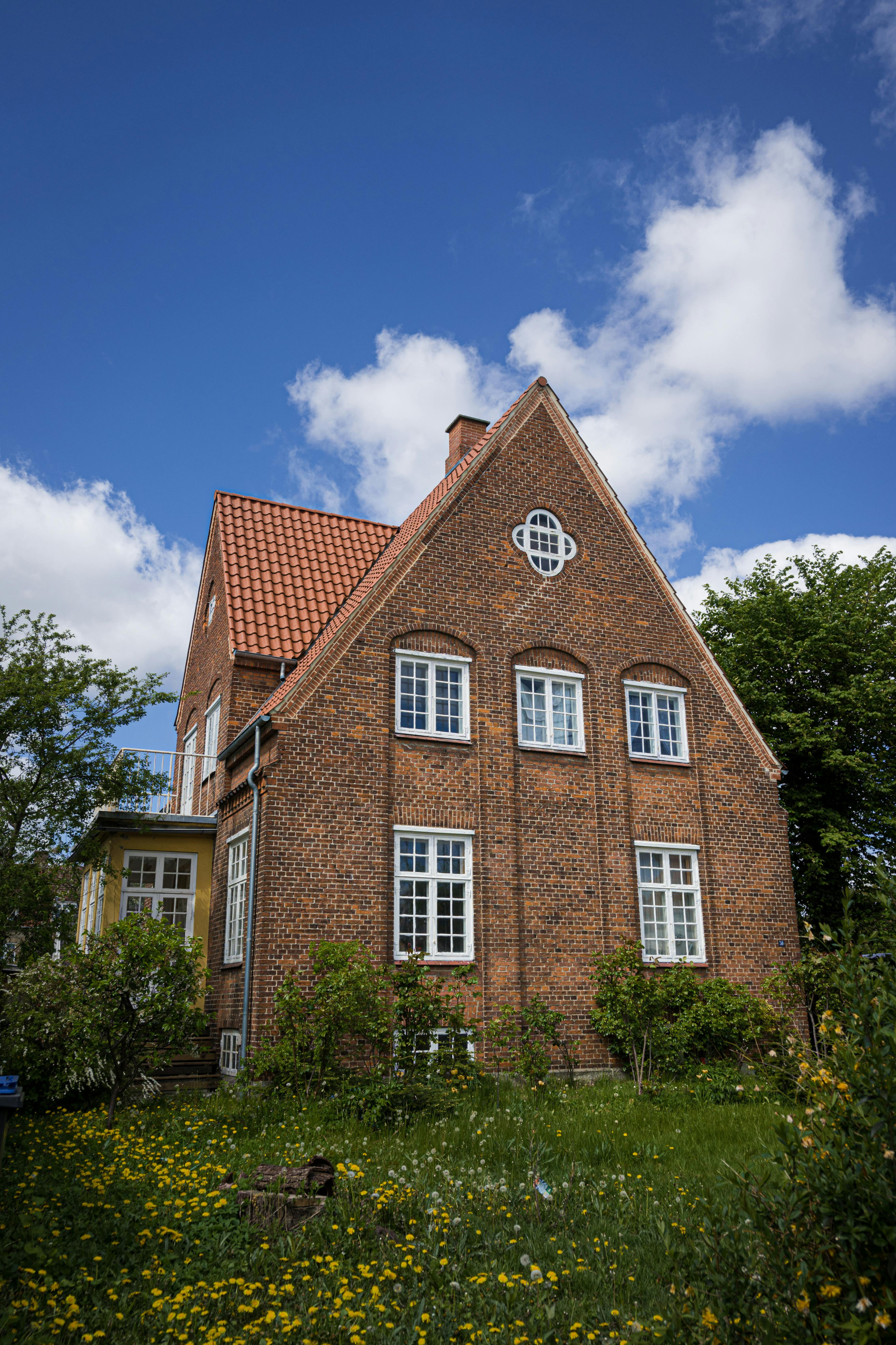 Brick villa with balanced wooden window proportions against a bright sky